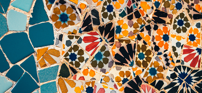 man cast i shadow paints on a canvas, with yellow and red flowery paintings on a tarp wall